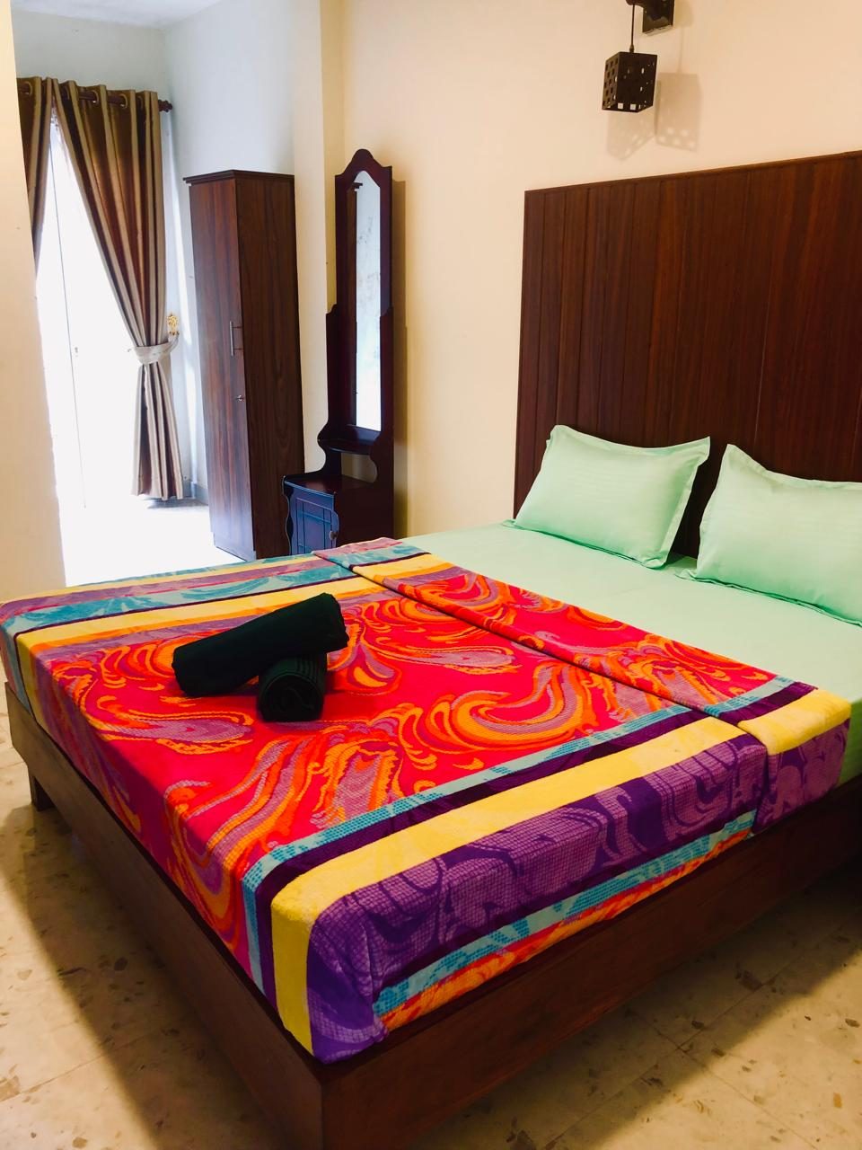 Deluxe Double Room bed with a colourful throw and a window to the garden