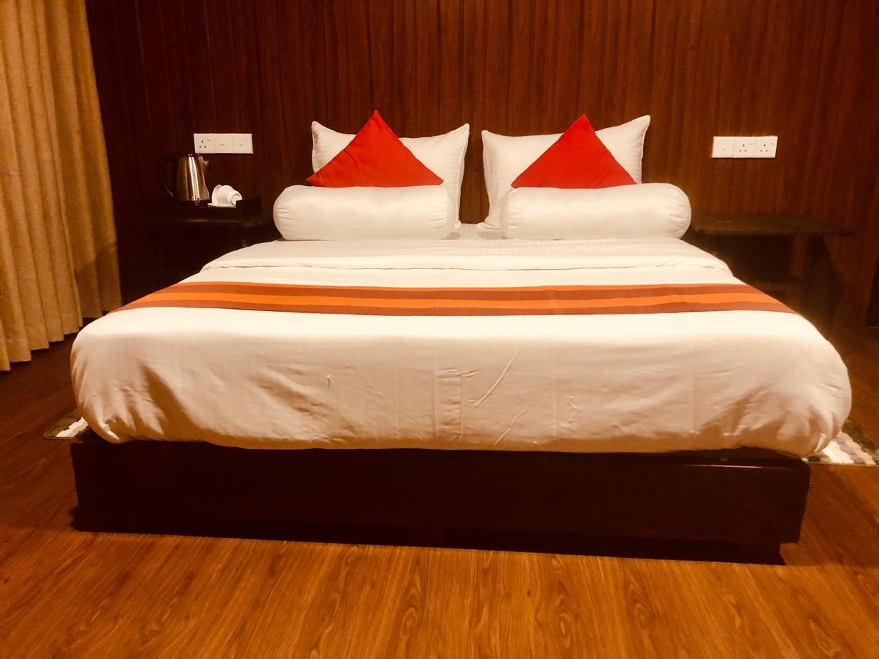 Double Room with Balcony — large double bed with red cushions and an orange runner